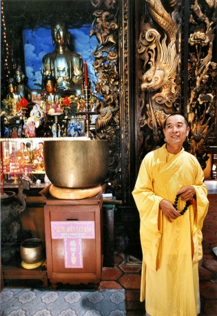 Dans un temple à Huet Benevolencia de un monje, frente a un cuenco de gong que marca las oraciones.