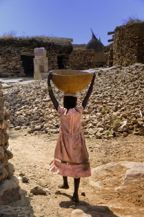 Djiguibombo Muchas tareas domésticas se delegan a los niños, como aquí una niña que lleva agua en una calabaza del pozo.